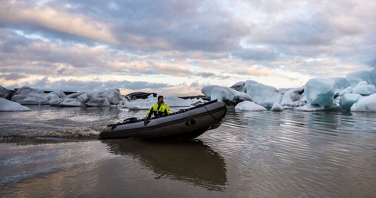 person in a raft with icebergs