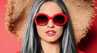 Portrait of young woman with beautiful grey colored hair on red background 